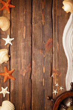 Arka plan - geminin direksiyon simidi, sahil kumu ve kabukları ahşap masa üzerinde Yatçılık