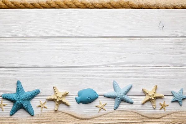 Seashells, sand and hawser on wooden board