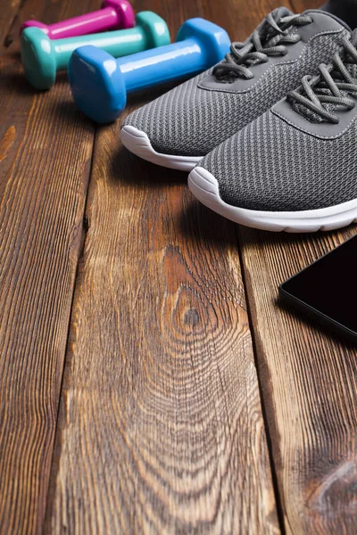 Smartphone Αθλητικά Παπούτσια Και Χρωματιστά Αλτήρες Στο Ξύλινο Τραπέζι — Φωτογραφία Αρχείου