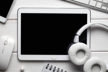 Beyaz boş ekran, kulaklık, akıllı telefon, bilgisayar klavye ve beyaz masa üstünde not etmek ile tablet