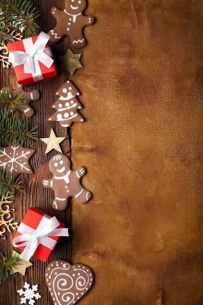 Christmas background - gingerbread cookies, gift boxes, stars and snowflakes and spruce tree on wooden and paper background