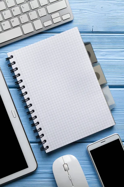 在蓝色木制背景上的带复印空间和现代电子产品的笔记本 — 图库照片