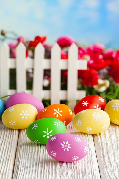 Huevos de Pascua coloridos y cerca blanca en el fondo de la naturaleza —  Fotos de Stock