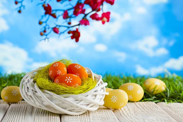 Wielkanocne jaja w gnieździe i drewniany stół na tle przyrody — Zdjęcie stockowe