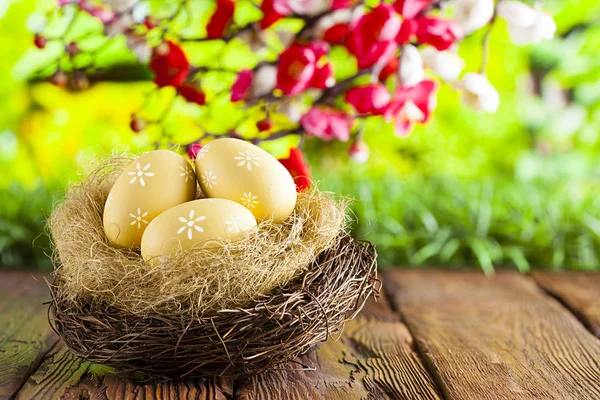 Tři malované velikonoční vejce v hnízdě na stůl a přírodní pozadí — Stock fotografie