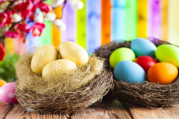 Пасхальные яйца на деревянном столе и абстрактном красочном фоне — стоковое фото