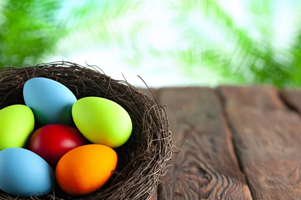 Ovos de Páscoa coloridos no ninho em mesa de madeira e natureza backg — Fotografia de Stock