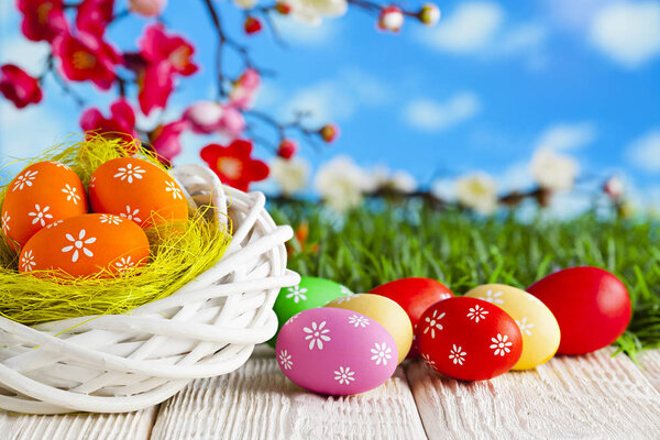 Easter eggs in the nest and wooden table on nature background