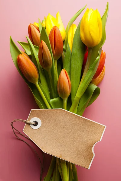 Buquê de tulipas coloridas e cartão de papel em branco em um backgr rosa — Fotografia de Stock