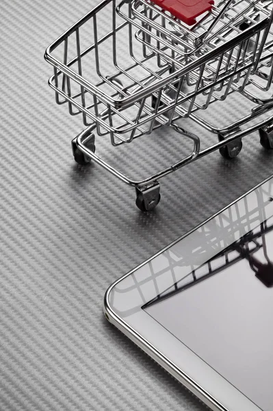 Trolley winkelwagentje en digitaal apparaat op koolstofvezel backgro — Stockfoto