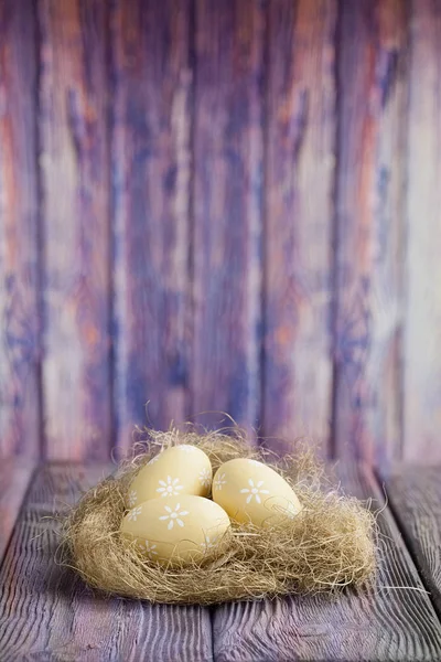 Ostereier im Nest und auf dem Tisch auf Holzgrund — Stockfoto