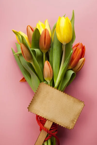 Buquê de tulipas coloridas e cartão de papel em branco em um backgr rosa — Fotografia de Stock