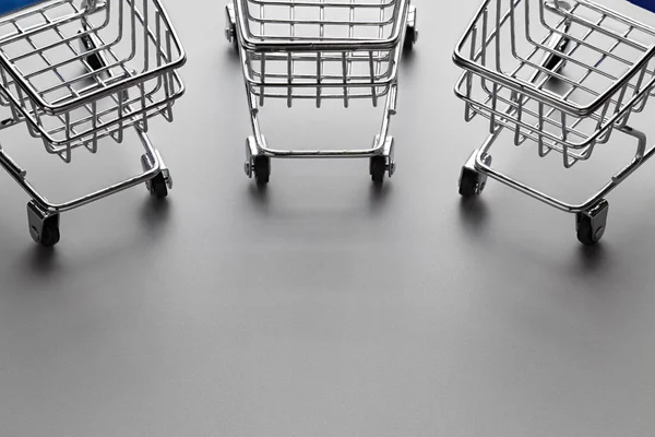 Three self-service shopping trolleys cart on carbon fiber backgr — Stock Photo, Image