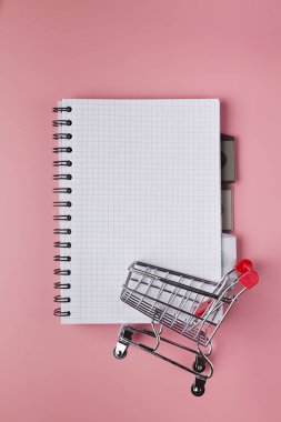 Pembe masada boş sayfa ve alışveriş sepeti ile defter