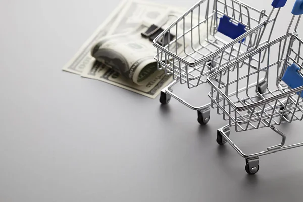 Shopping carts and dollar bills on a gray table — Stock Photo, Image