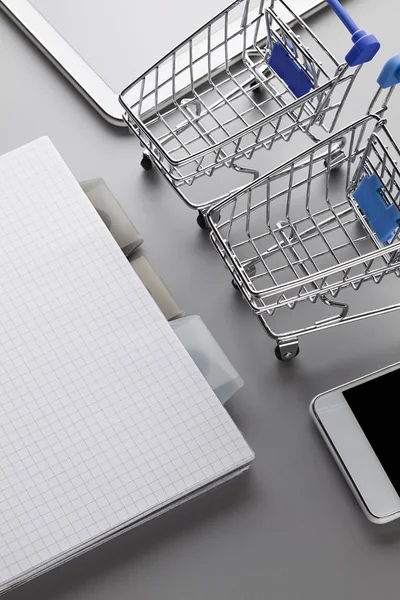 Twee winkelwagentjes, notebook met een blanco pagina, moderne witte cel — Stockfoto