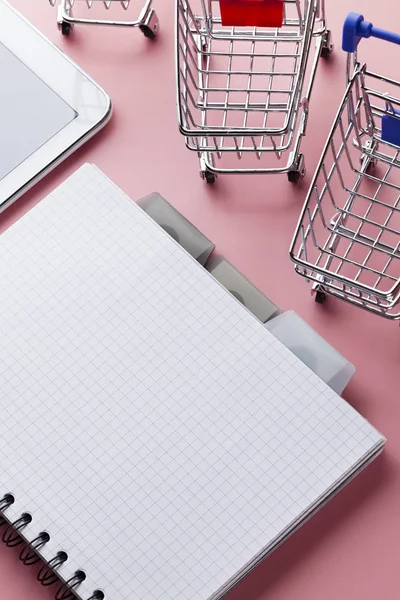 Einkaufswagen, weißes Tablet und Notizbuch mit einer leeren Seite auf der Seite — Stockfoto