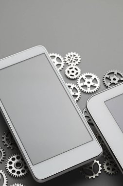 Gri masada modern akıllı telefon ve küçük dişliler