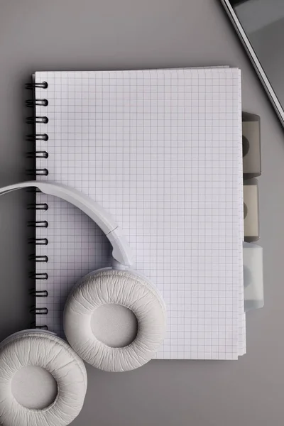 White headphones and notebook with blank page on gray table — Stock Photo, Image