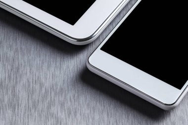 Alüminyum bir masa üzerinde modern beyaz cep telefonu ve tablet