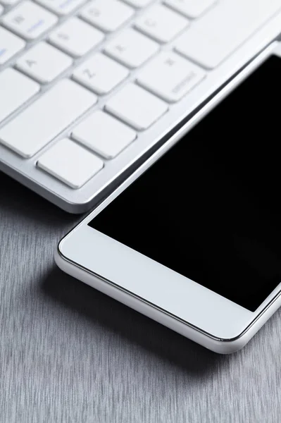 Téléphone portable blanc moderne et clavier d'ordinateur sur un alumin gris — Photo
