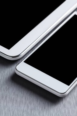 Alüminyum bir masa üzerinde modern beyaz cep telefonu ve tablet