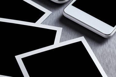 Gri üzerine modern beyaz cep telefonu, tablet ve kağıt fotoğraf çerçevesi 