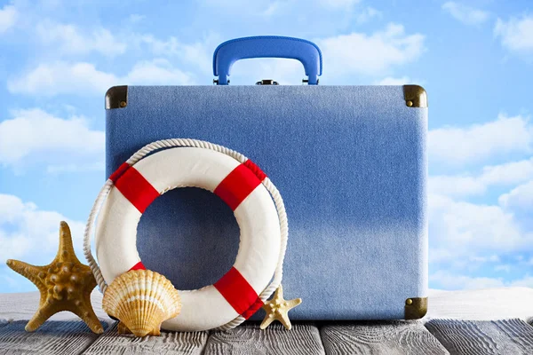 Сумка для летнего отдыха - чемодан, спасательный круг и снаряды на пляже — стоковое фото