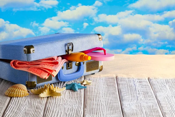 Symbol prázdninového výletu-kufr plný prázdninových předmětů na dřevěném — Stock fotografie