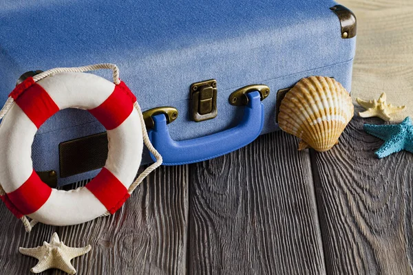 Holiday utazási bőrönde, mentőgyűrűt és héjat a fából készült asztal — Stock Fotó