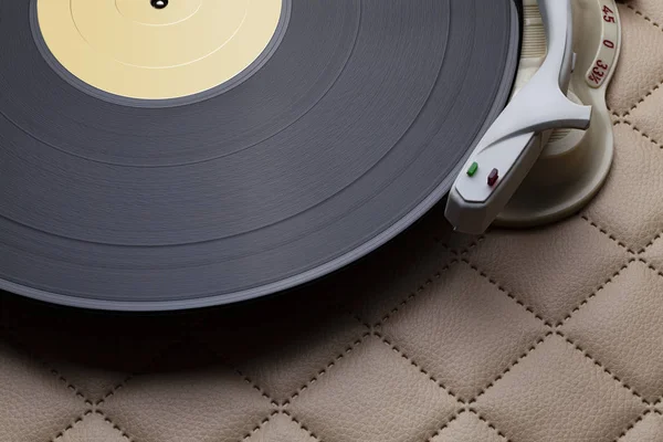 Vintage record player with vinyl record on leather background