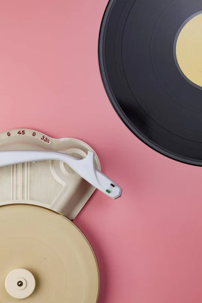 Vintage record player with vinyl record on pink background