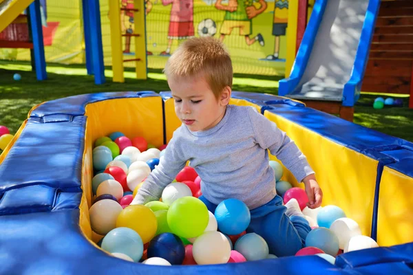 Petit garçon jouant avec des balles colorées dans l'aire de jeux du parc — Photo