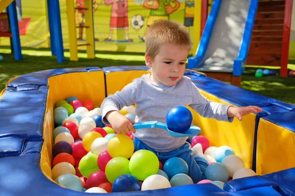 Garçon joue dans la piscine de balle à l'aire de jeux pour enfants — Photo