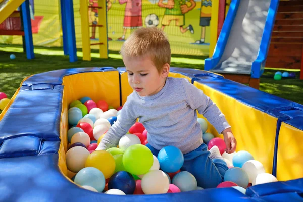 Petit garçon jouant avec des balles colorées dans l'aire de jeux du parc — Photo