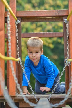 3 yaşında tatlı bir çocuk, sonbaharda dışarıda oyun alanında eğleniyor.