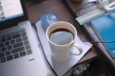 Üzerinde defter ve kahve olan çalışma masası.