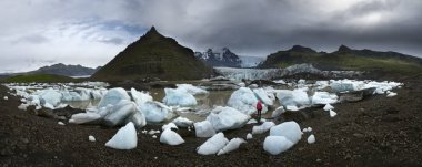 Kadın kırmızı ayakta ve İzlanda'daki buzul göl kıyısına arıyor