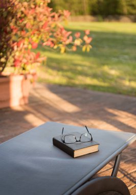 manzara ve günbatımı ışık önünde kapalı kitap ile gözlük