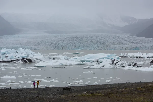 在冰岛冰川泻湖前散步的两个人 — 图库照片