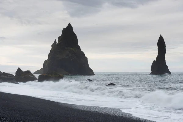 Famous Reynisdrangar rock formations at black Reynisfjara Beach. Coast of the Atlantic ocean near Vik, southern Iceland.