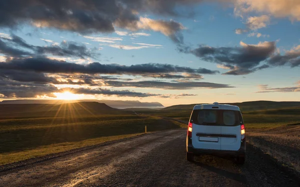 Gravel road along the valley at sunset with lonely car. Car travel in Iceland