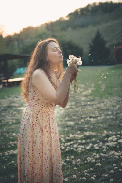 漂亮的女孩吹蒲公英在夏季公园 绿草美丽的自然 — 图库照片
