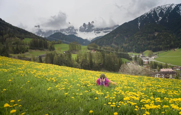 Active healthy woman having rest on beautiful meadow covered with flowers. Portrait of happy smiling young woman resting of mountains clearing during hike holidays