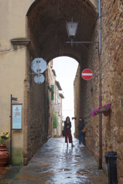 Pienza/İtalya-05/05/18: iki kadın yağmur Pienza, Toscana, İtalya için eski en güzel kentlerinden biri eski kemer altında gizleme