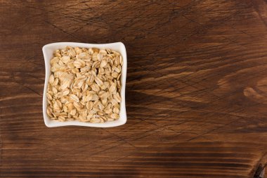 Yulaf veya yulaf gevreği kapta ahşap arka plan üzerinde yuvarlandı. Sağlıklı yaşam tarzı, sağlıklı beslenme kavramı. Üstten görünüm 