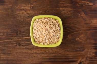 Yulaf veya yulaf gevreği kapta ahşap arka plan üzerinde yuvarlandı. Sağlıklı yaşam tarzı, sağlıklı beslenme kavramı. Üstten görünüm 