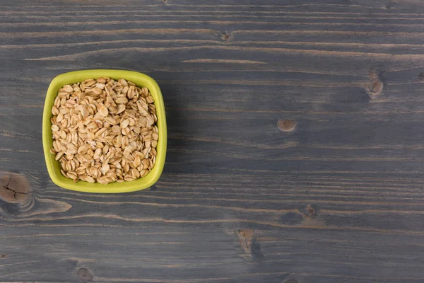 Rolled oats or oat flakes in bowl on wooden background. Healthy lifestyle, healthy eating concept. Top view