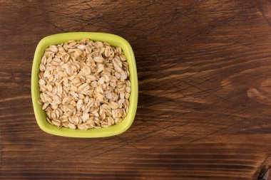 Yulaf veya yulaf gevreği kapta ahşap arka plan üzerinde yuvarlandı. Sağlıklı yaşam tarzı, sağlıklı beslenme kavramı. Üstten görünüm 