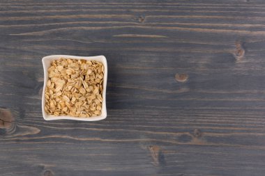 Yulaf veya yulaf gevreği kapta ahşap arka plan üzerinde yuvarlandı. Sağlıklı yaşam tarzı, sağlıklı beslenme kavramı. Üstten görünüm 